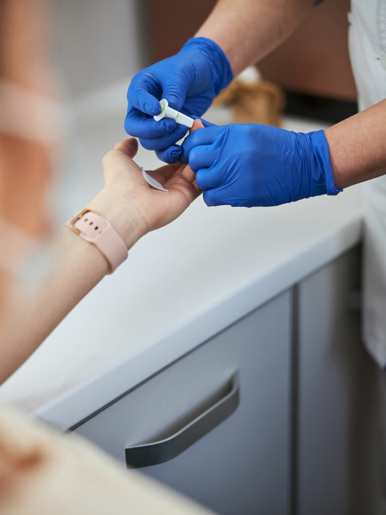 Phlebotomy technician pricking patient's finger