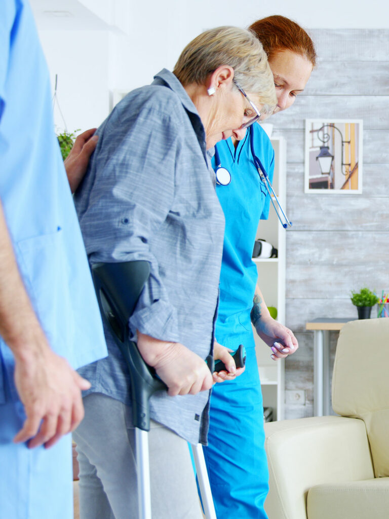two rehab nurses assisting patient with walking exercises