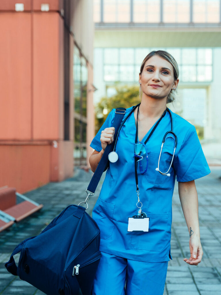 travel nurse in scrubs carrying duffel bag